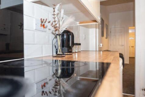 A sleek, modern kitchen featuring a glossy blac...