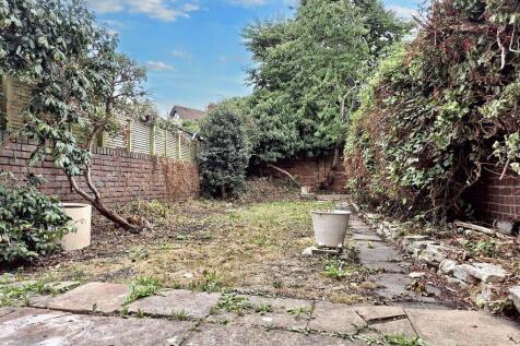 A charming garden space featuring a paved patio...