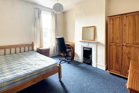 A bright double bedroom featuring a wooden bed ...