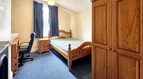 A cozy double bedroom featuring a wooden bed fr...