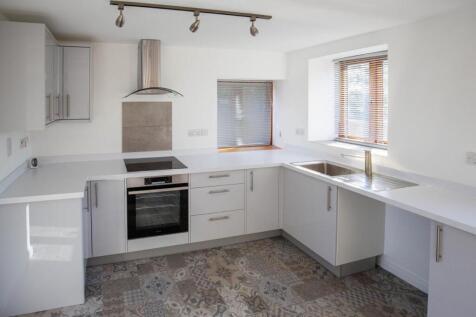 A modern and bright kitchen featuring white cab...