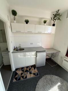 A compact, modern kitchen area featuring white ...