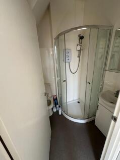 A compact bathroom featuring a corner shower wi...