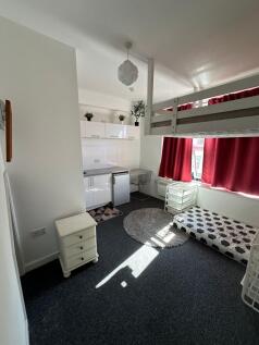 A compact, well-lit student room featuring a lo...