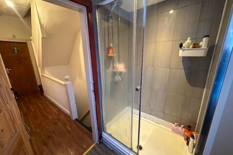 A compact bathroom featuring a glass-enclosed s...