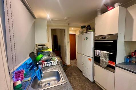 A compact kitchen featuring modern white cabine...