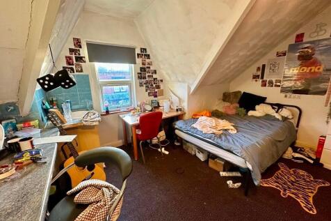 A cozy single bedroom featuring a sloped ceilin...