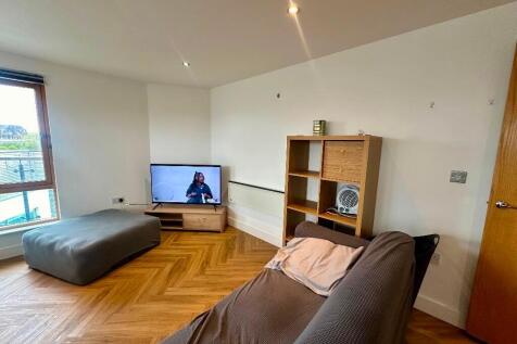 A modern living room featuring warm wooden floo...