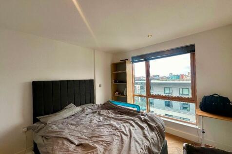 A bright double bedroom featuring a large windo...