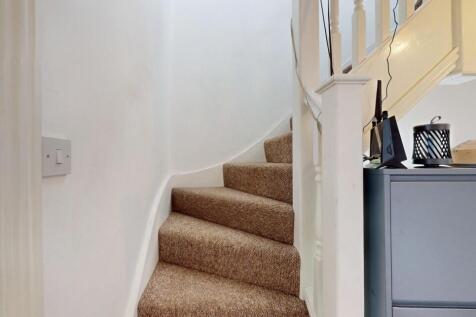 Well-maintained carpeted staircase with white w...