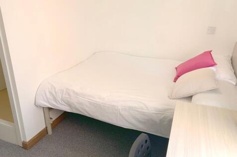 A neat and tidy single bedroom featuring a simp...