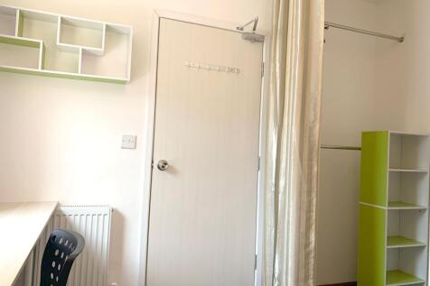 A bright and tidy single bedroom featuring mode...