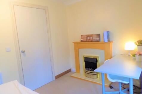 A cozy single bedroom featuring a tidy workspac...
