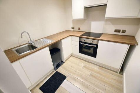 A modern, clean kitchen featuring a sleek woode...