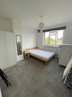 A bright double bedroom featuring a large windo...