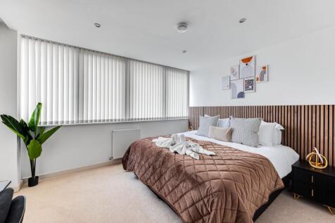 A modern master bedroom featuring a large, comf...