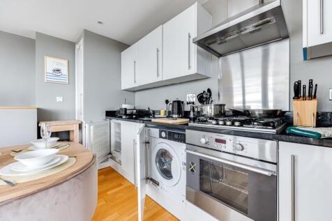 Modern kitchen with sleek white cabinetry, blac...