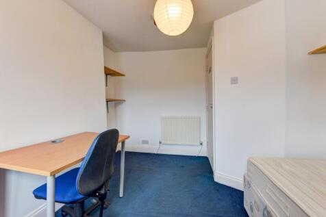 A neat and simple student bedroom featuring a d...