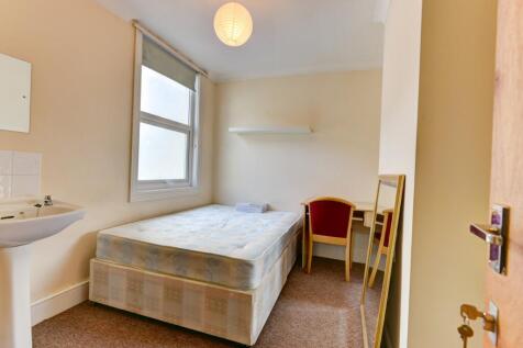 A compact, tidy bedroom featuring a single bed ...
