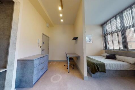 A well-lit single bedroom featuring a comfortab...