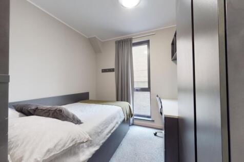 A compact, well-maintained bedroom illuminated ...