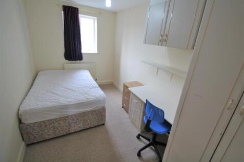 A small, clean bedroom with a single bed, a win...