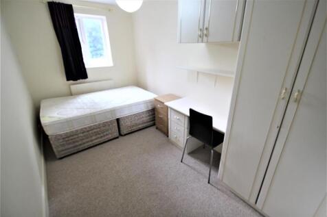 A bright and simple student bedroom featuring a...