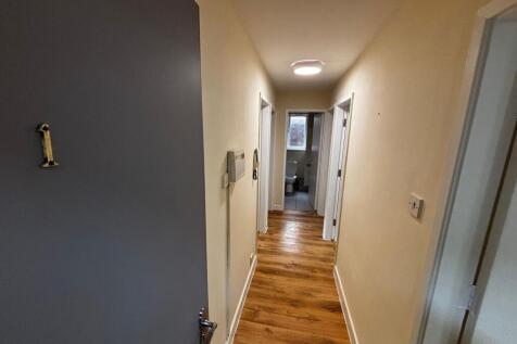 A bright, clean bathroom with a toilet and wind...