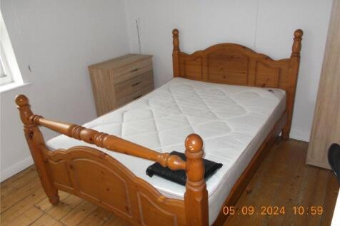 A cozy double bedroom featuring a wooden bed fr...