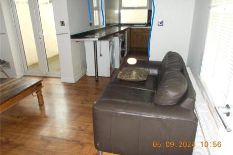 A compact living room featuring wooden flooring...