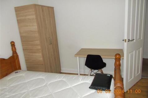 A neat and simple bedroom featuring a wooden be...