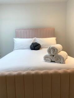 A cozy double bedroom featuring a plush, uphols...