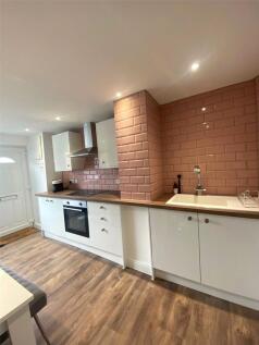 A modern kitchen featuring white cabinetry, a s...