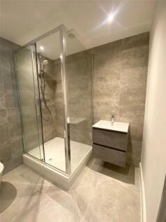 A modern bathroom featuring a sleek glass showe...