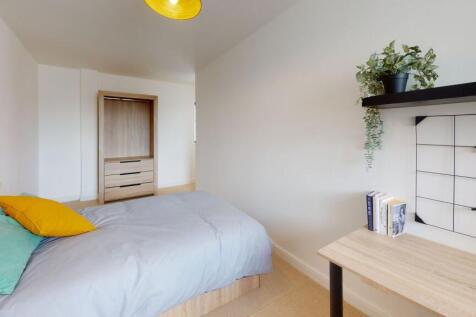 A bright and tidy bedroom featuring a neatly ma...