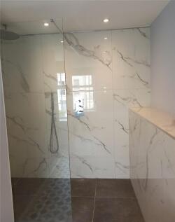 A sleek and modern bathroom featuring a walk-in...