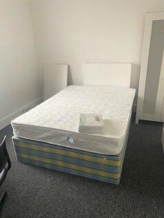 A simple, clean bedroom featuring a single bed ...