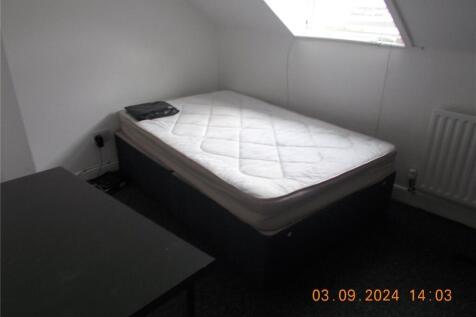 A simple, tidy single bedroom featuring a mattr...
