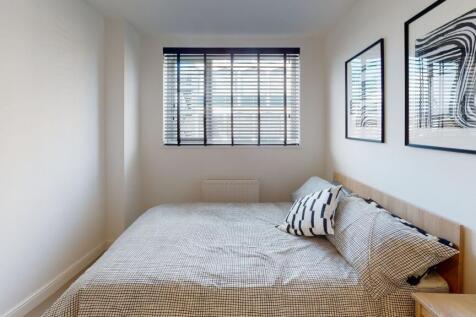 A cozy bedroom featuring a neatly made bed with...