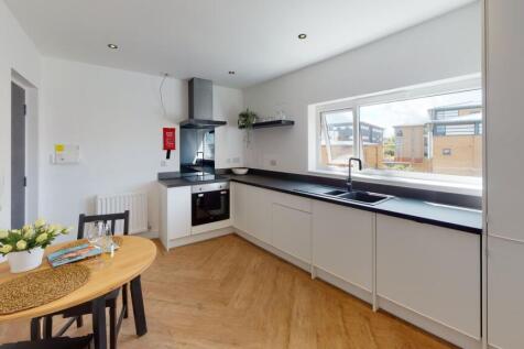 Modern kitchen with sleek white cabinets, a lar...