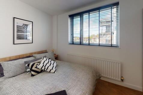 A bright and cozy bedroom featuring a large win...