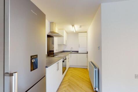 A modern, clean kitchen featuring white cabinet...