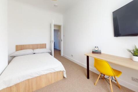 A tidy and bright bedroom featuring a comfortab...
