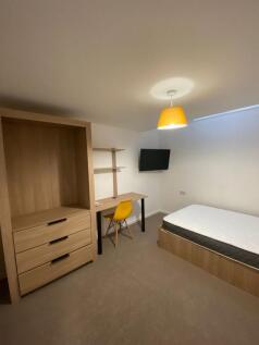 A cozy single bedroom featuring a wooden bed fr...
