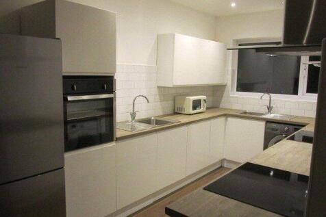 Modern kitchen featuring sleek white cabinetry,...