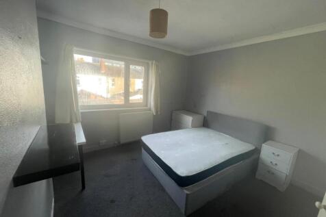 A simple bedroom with a window providing natura...