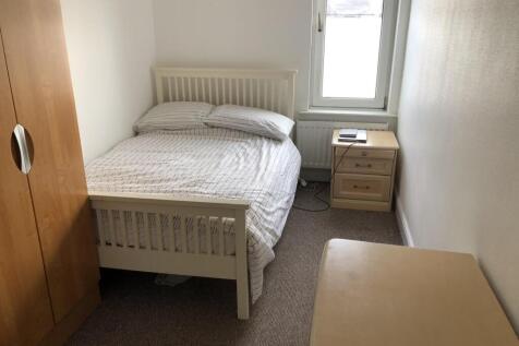 A tidy and simple bedroom featuring a white bed...