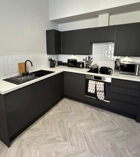 Modern kitchen with sleek black cabinets, clean...
