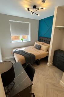 A modern, well-lit bedroom featuring a comforta...