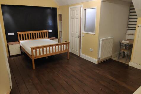 A spacious double bedroom featuring a wooden be...